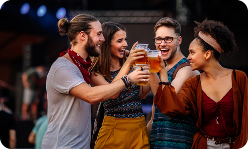 Group of young adults holding drinks and doing cheers at an outdoor event