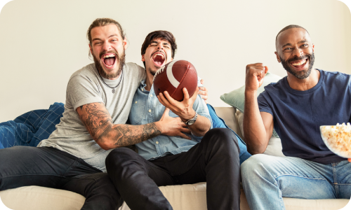 three men sitting on a sofa watching football