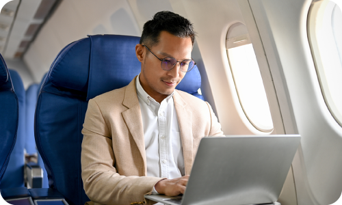 Man on a plane working on his laptop